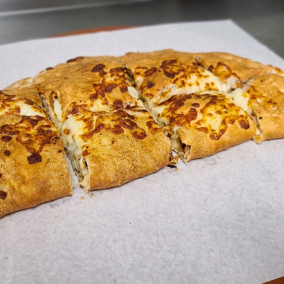 Golden-brown cheesy stuffed bread, sliced into pieces and served on parchment paper.
